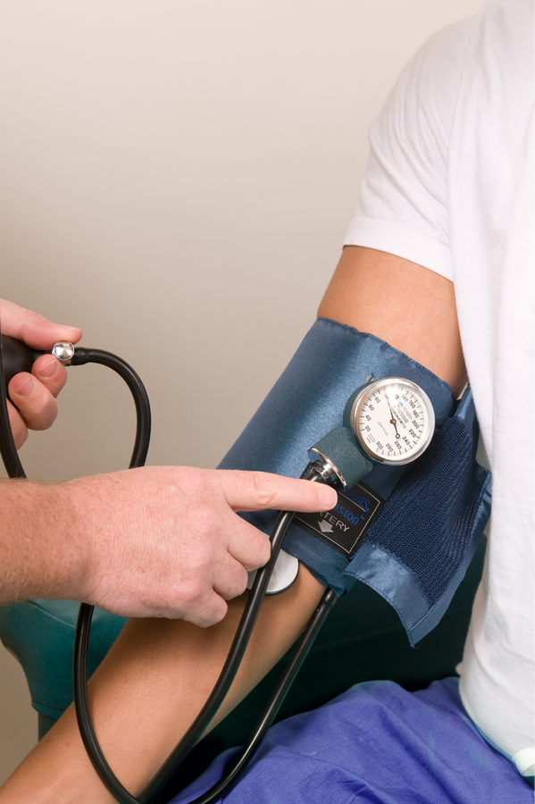 Healthcare practitioner in the process of conducting a blood pressure examination upon a seated male patient in a clinical setting. Courtesy of the Public Health Image Library, Centers for Disease Control and Prevention.